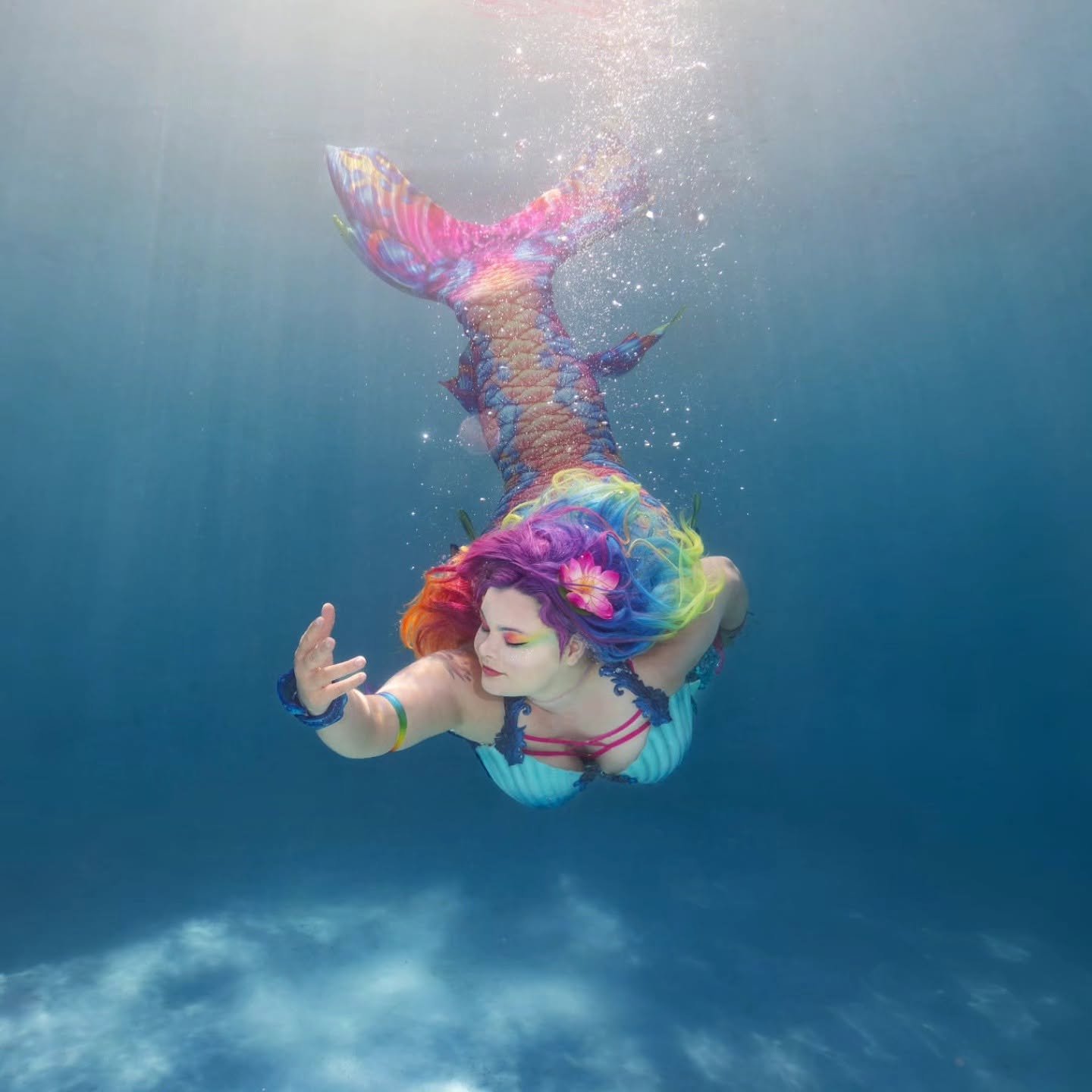 WhimSea Waves swimming underwater in a vibrant rainbow-colored mermaid tail.